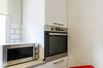 Modern kitchen scene with microwave, oven, and white cabinets. Clean lines and neutral tones