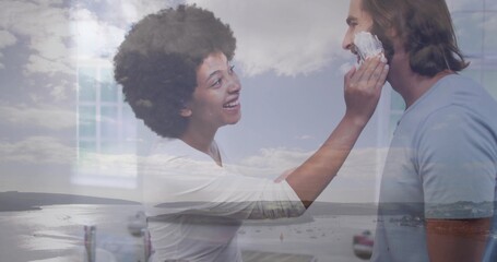 Couple applying shaving foam at bathroom counter with faucet mirror frame glass window harbor view