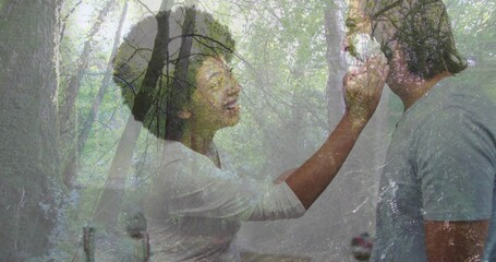 Feeding woman wearing white shirt giving spoonful to man in grey shirt in kitchen, chrome faucet
