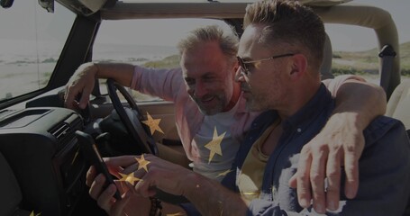 Examining smartphone, two mature men sitting in open-top SUV near shoreline, steering wheel showing