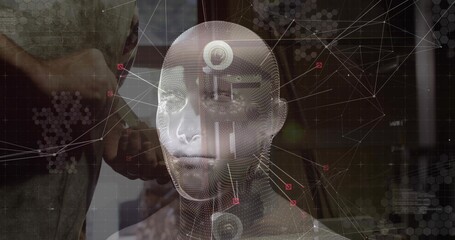 Male holding handheld scanner and pointing at holographic 3D head model in lab, with data nodes