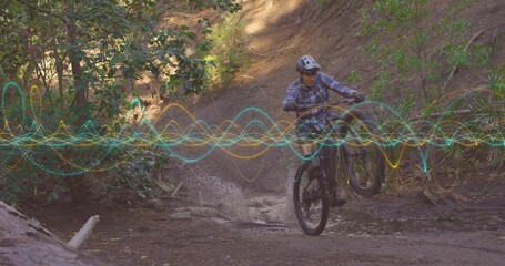 Riding trail bike wearing helmet and goggles splashing through forest creek, with digital waveforms