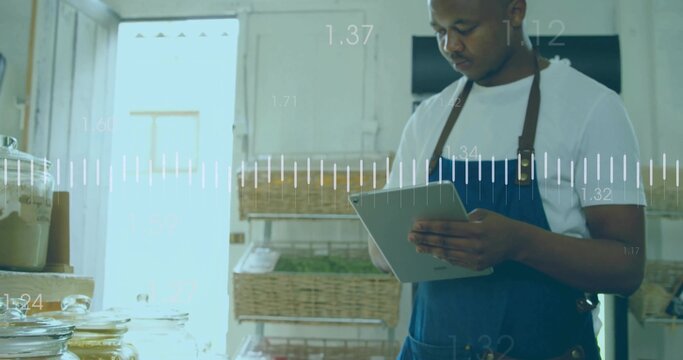 Store clerk wearing blue apron checking tablet screen in pantry, with wicker baskets, glass jars - Powered by Adobe