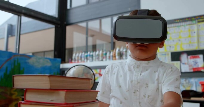 Exploring virtual reality world boy wearing VR headset at classroom table, with globe and books
