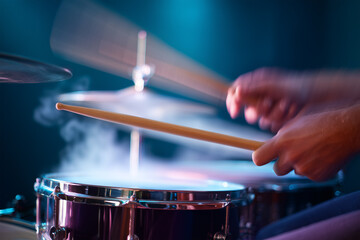 Drummer performing live on stage with colorful lights at night