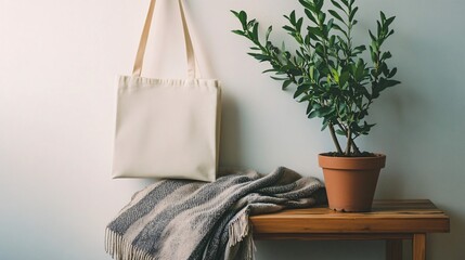 Tote bag hanging on wall near plant in pot on wooden surface.