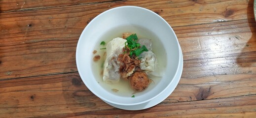 Bakso malang served in a white bowl on wooden table. Indonesian food dish