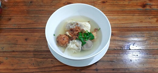 Bakso malang served in a white bowl on wooden table. Indonesian food dish