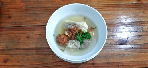 Bakso malang served in a white bowl on wooden table. Indonesian food dish