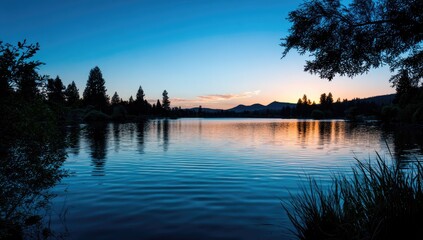 Fototapeta premium Serene lake scene at sunrise, showcasing tranquil water reflecting a colorful sky.