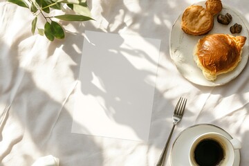 Blank card with coffee pastry and plant on white fabric background.