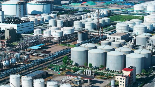 Aerial shot of a large depot with rows of cylindrical oil and gas storage tanks in an industrial zone.