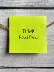 Think positive text written on notepaper close up background. Stock photo.