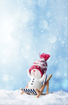 One little snowmen on deck chair in caps on snow in the winter. Background with a funny snowman. Christmas card.