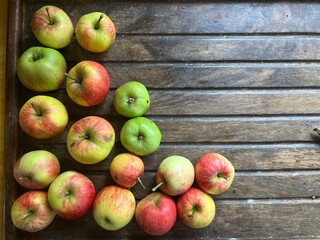 Close up of ripe red and green apples on a  clear wooden table surface background the fruit freshly harvest organic allotment orchard garden in Summer interior flat lay top view with copy space
