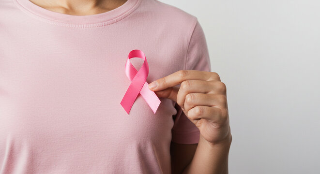 Woman proudly displays pink ribbon for breast cancer awareness, symbolizing hope, support, and early detection efforts for a healthier future.