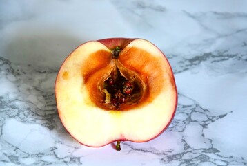 Sliced apple with a darkened core and signs of spoilage. Concept of rotten fruits, food waste, and...