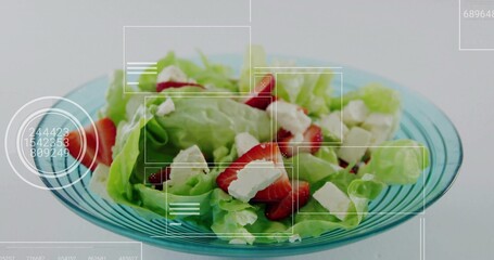Turquoise bowl sitting in kitchen, with lettuce, sliced strawberries, cheese cubes and UI overlays