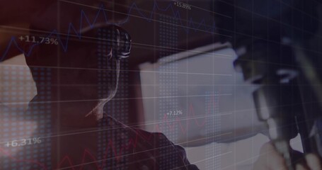 Recording host wearing headphones in studio, with microphone, computer monitor and market data