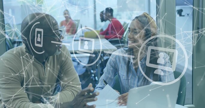 Coworkers reviewing documents and pointing at laptop in coworking space, with network overlay