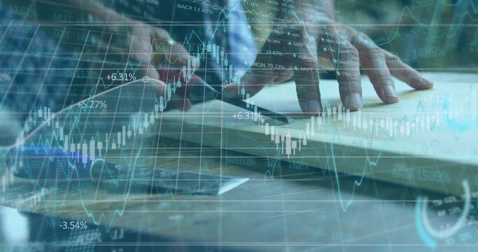 Business professional placing hands on laptop on desk in office with financial chart overlays