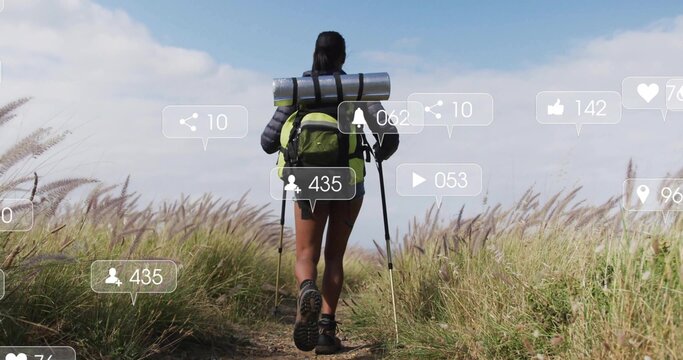 Walking female hiker carrying bright green backpack with trekking poles along rural trail, AR icons