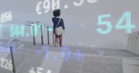 Mid adult woman descending concrete stairs at transit station, with currency data, copy space