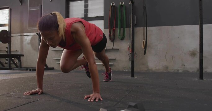 African American woman wearing sportswear performing mountain climber exercise on rubber gym floor