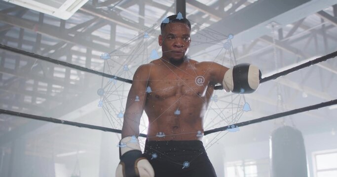 Shirtless white-gloved boxer leaning on ring ropes in gym, with punching bags and network overlay