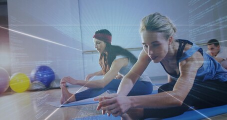 Woman in blue tank top stretching forward on yoga mat in yoga studio, with exercise balls