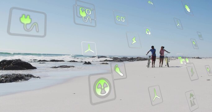 Walking couple wearing casual clothes along beach with bicycle, longboard, energy icons, copy space - Powered by Adobe