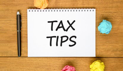 Tax tips symbol. Concept word Tax tips on beautiful white note. Black pen, colored paper. Beautiful wooden background. Business tax tips concept. Copy space.