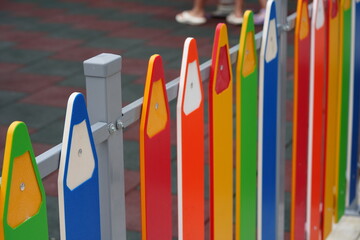 Colorful fence in the shape of pencils at a children’s playground. Bright red, orange, green, and blue elements — concept of childhood, creativity, design, and education.