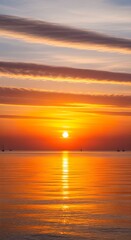 Fototapeta premium Vibrant orange sunset over calm ocean water with scattered sailboats under striped clouds