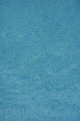 Blue water surface in a swimming pool with sunlight reflections. Clear aquatic texture — refreshing summer background symbolizing purity, relaxation, and travel.