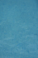 Blue water surface in a swimming pool with sunlight reflections. Clear aquatic texture — refreshing summer background symbolizing purity, relaxation, and travel.