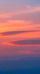 Dramatic sunset sky with vibrant orange pink and purple clouds transitioning into a deep blue horizon