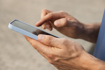 Man using and texting mobile phone. Check apps, focused on device, chatting or browsing internet. Online. Outdoors.