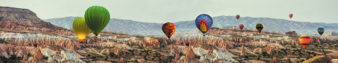 Panoramic view with colorful hot air balloons over Cappadocia rocky valleys and mountains, ideal...