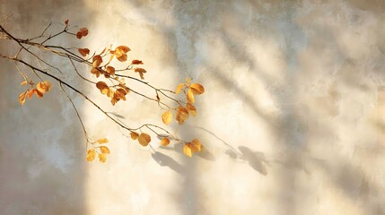 A branch with golden leaves casts a soft shadow on a textured wall, creating a warm and inviting atmosphere in the gentle light