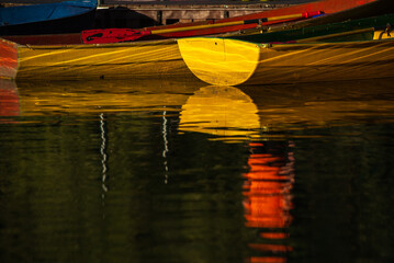 Old rowboats at the pier. Colorful colors. In the rays of the setting sun. Warm colors. Reflection in the water. Autumn days on the pond.