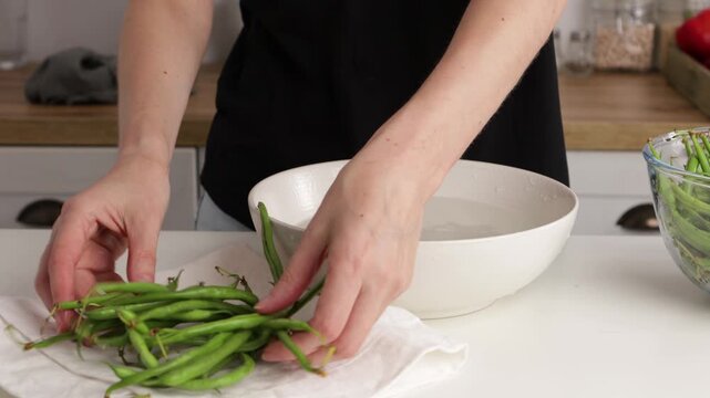hands washing green beans in bowl and put on table