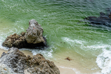 waves crashing on beach with rocks