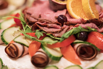 Open sandwich with roast beef cucumber orange and olives.