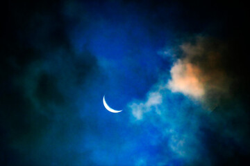 A serene crescent moon peeks through the clouds