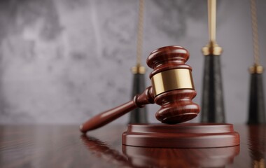 Legal Gavel and Scales of Justice: A close-up captures a wooden gavel resting on its sound block, with the iconic scales of justice delicately in the background. A symbol of law.