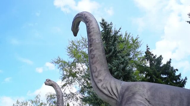 Two large dinosaur figures in the park in summer.