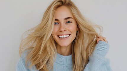 Obraz premium Smiling woman with flowing blonde hair wearing a cozy blue sweater, radiating joy and warmth, creating an inviting atmosphere with her expressive demeanor
