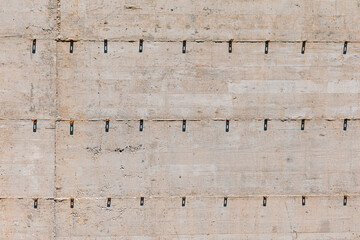 Concrete wall surface with horizontal lines and dark metal formwork tie marks, creating an industrial, textured background