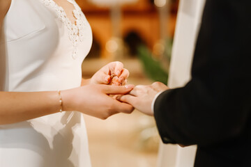 Bride and groom exchanging wedding rings during church ceremony, close-up of hands with rings...